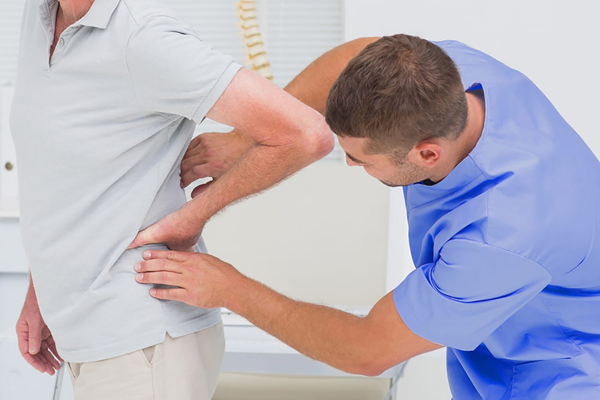 پزشک در حال معاینه فیزیکی کمر بیمار