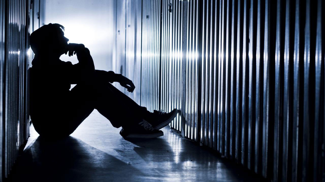 پسری تنها در راهرو و تاریکی نشسته است